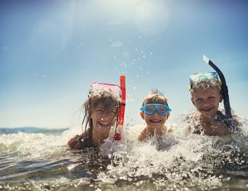 kids in water at beach with snorkels and goggles on their heads