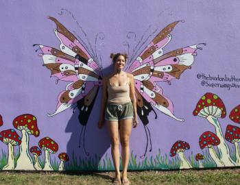 Artist Kennedy Fletcher stand amidst one of her butterfly murals.