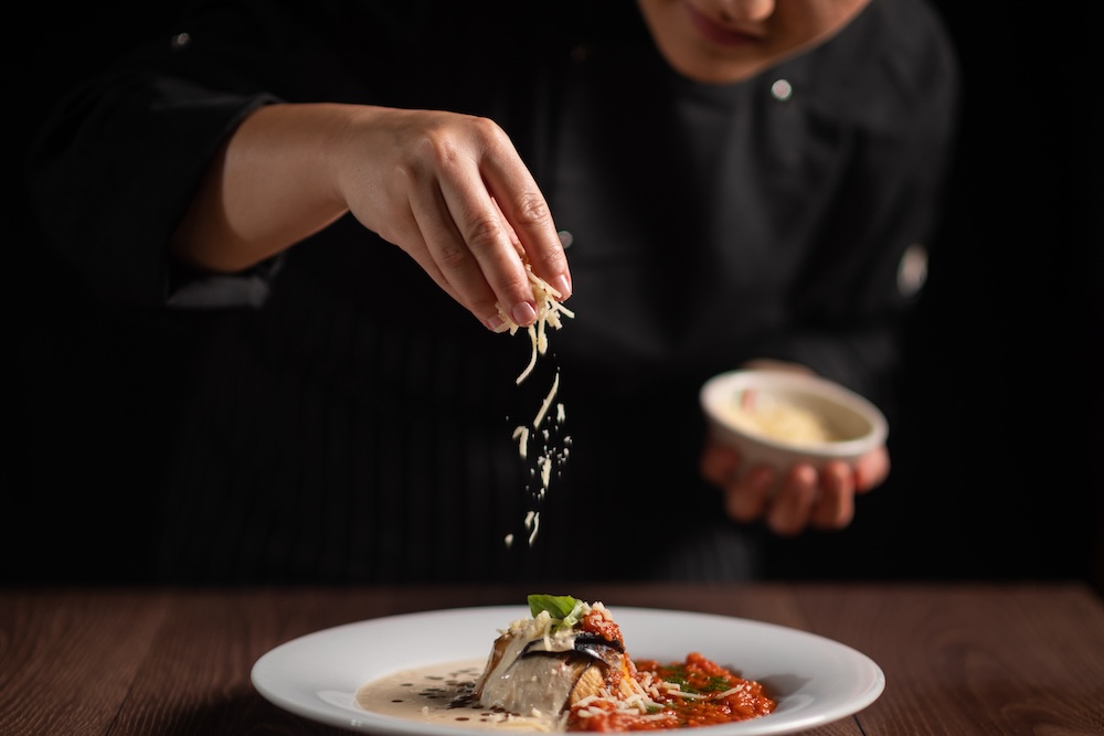 chef putting cheese on pasta dish