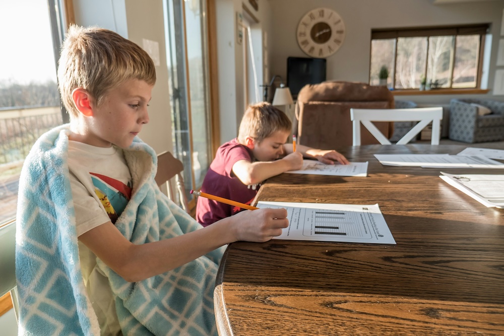 two boys sitting at table working on homework