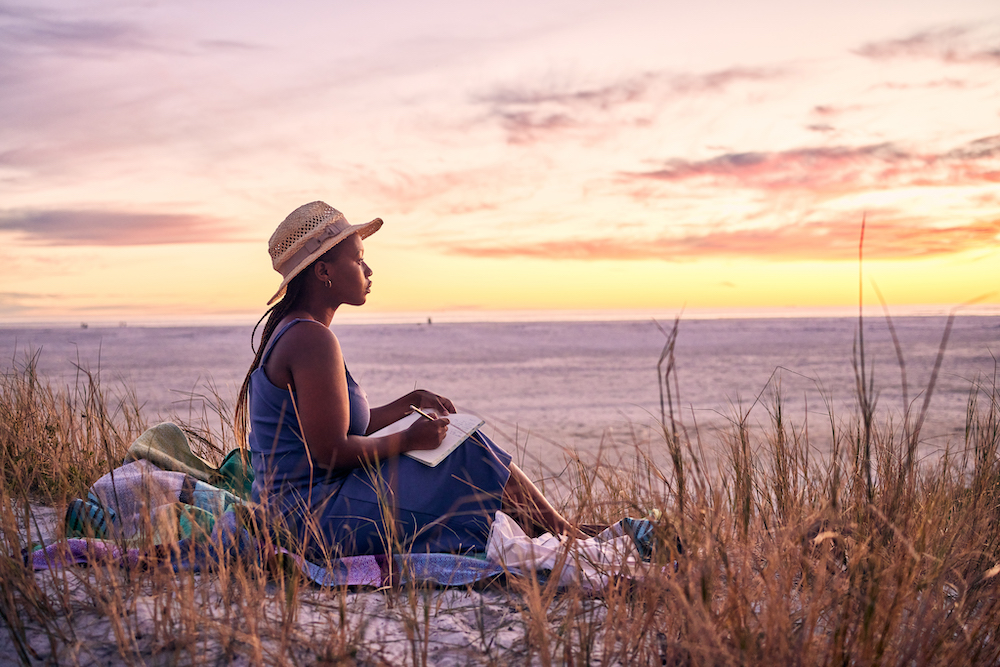 girl sitting on beach with notebook